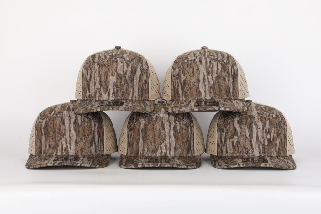 Five camo trucker hats with khaki perforated side panels, ready for custom patches