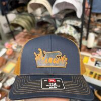 Navy and gold trucker hat with a layered patch of a pointing bird dog in tall grass