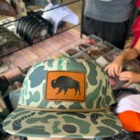 Green duck camo flat bill hat with an engraved leather bison patch