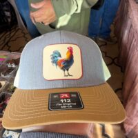 Heather blue trucker hat with a brown bill and a full-color rooster patch